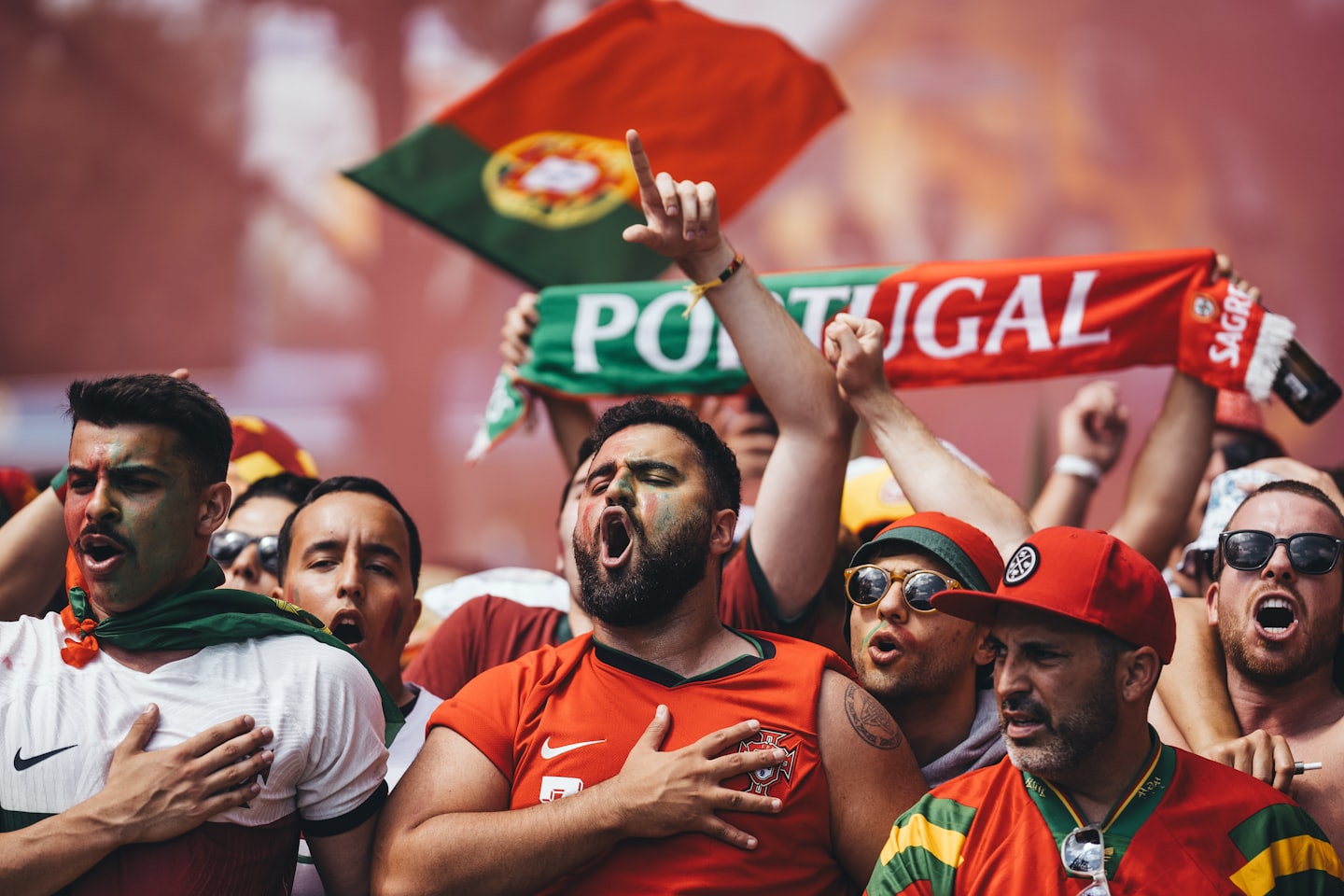 Tifosi di calcio con maglie rosse e verdi esultano con il viso dipinto.